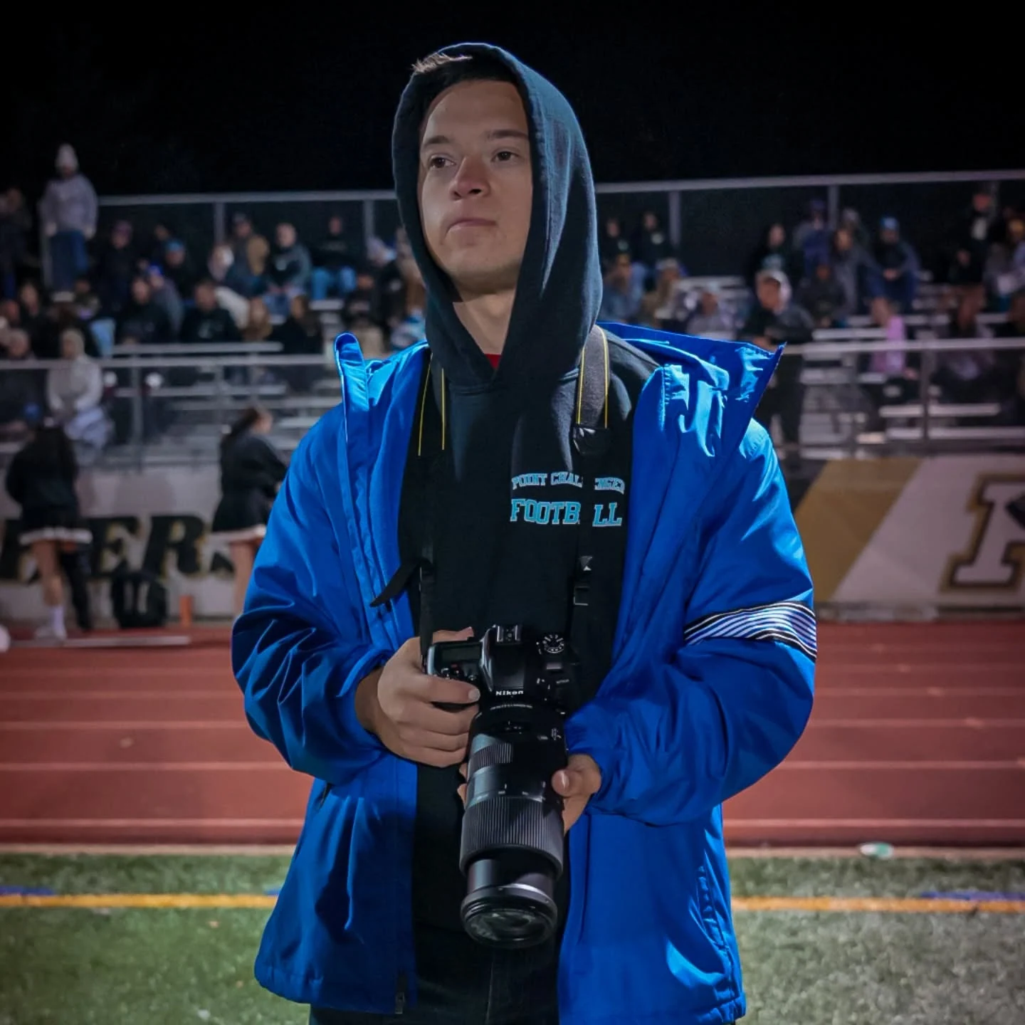 David on the sideline at a night football game, holding his Nikon camera