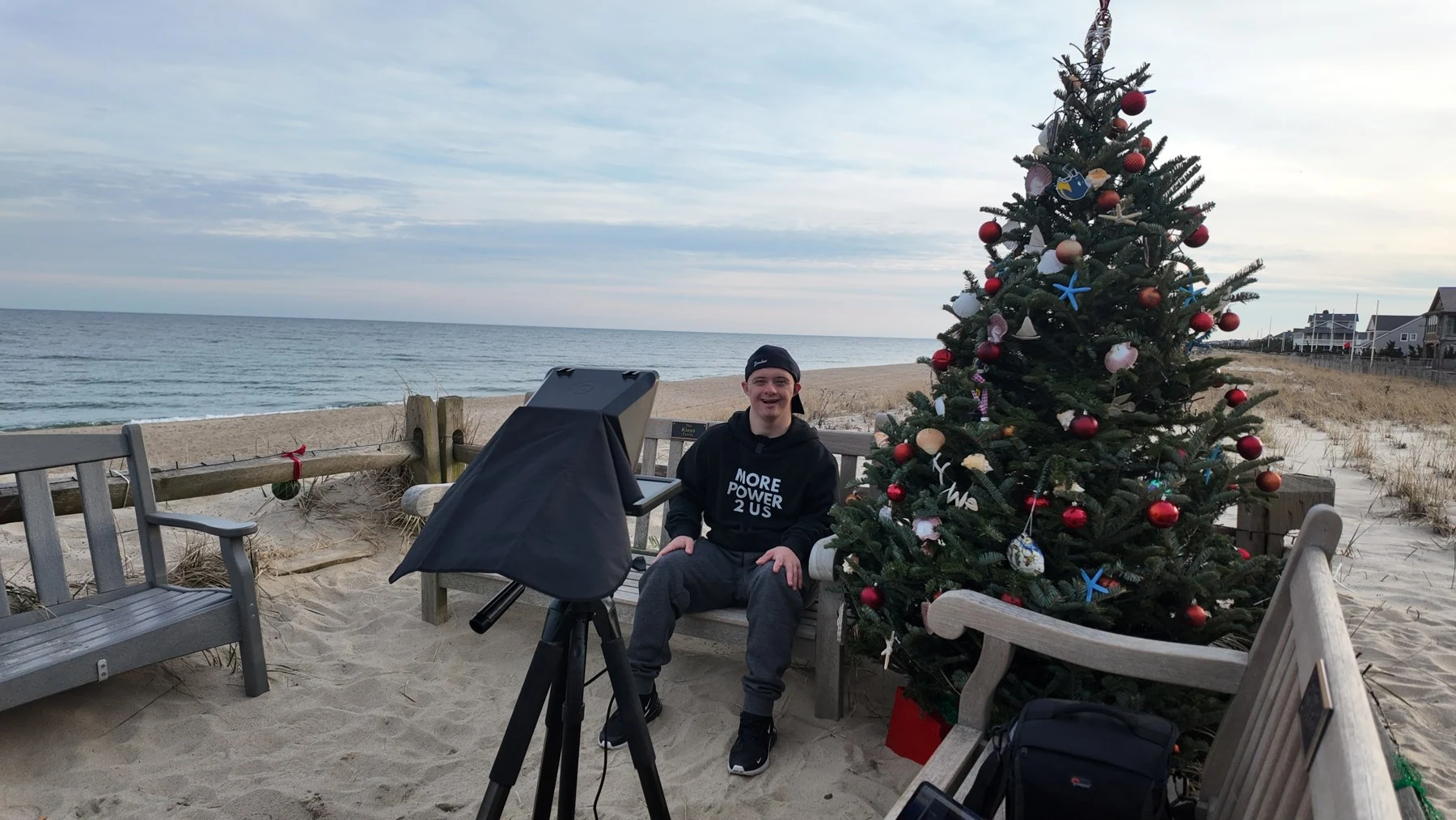 Matt recording outdoors by the beach, with a camera and teleprompter in front of him